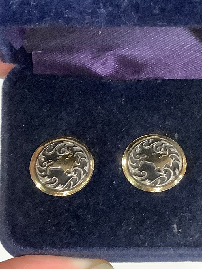 A pair of round gold-toned stud earrings with an engraved floral or scroll pattern, displayed on a dark blue velvet jewelry box.