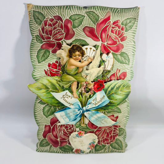Antique Victorian stand-up Valentine card with pop-out cherub and white dove, red roses, green leaves, and blue ribbon reading “Love’s Message” and “to my Valentine.”