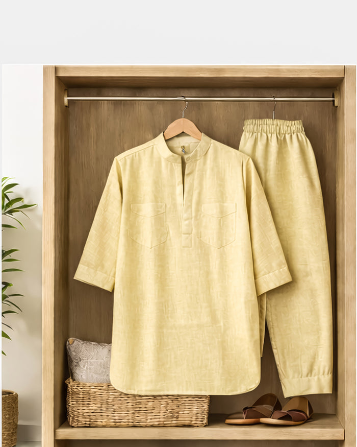 Light yellow outfit with shirt and pants hanging on a wooden wardrobe.